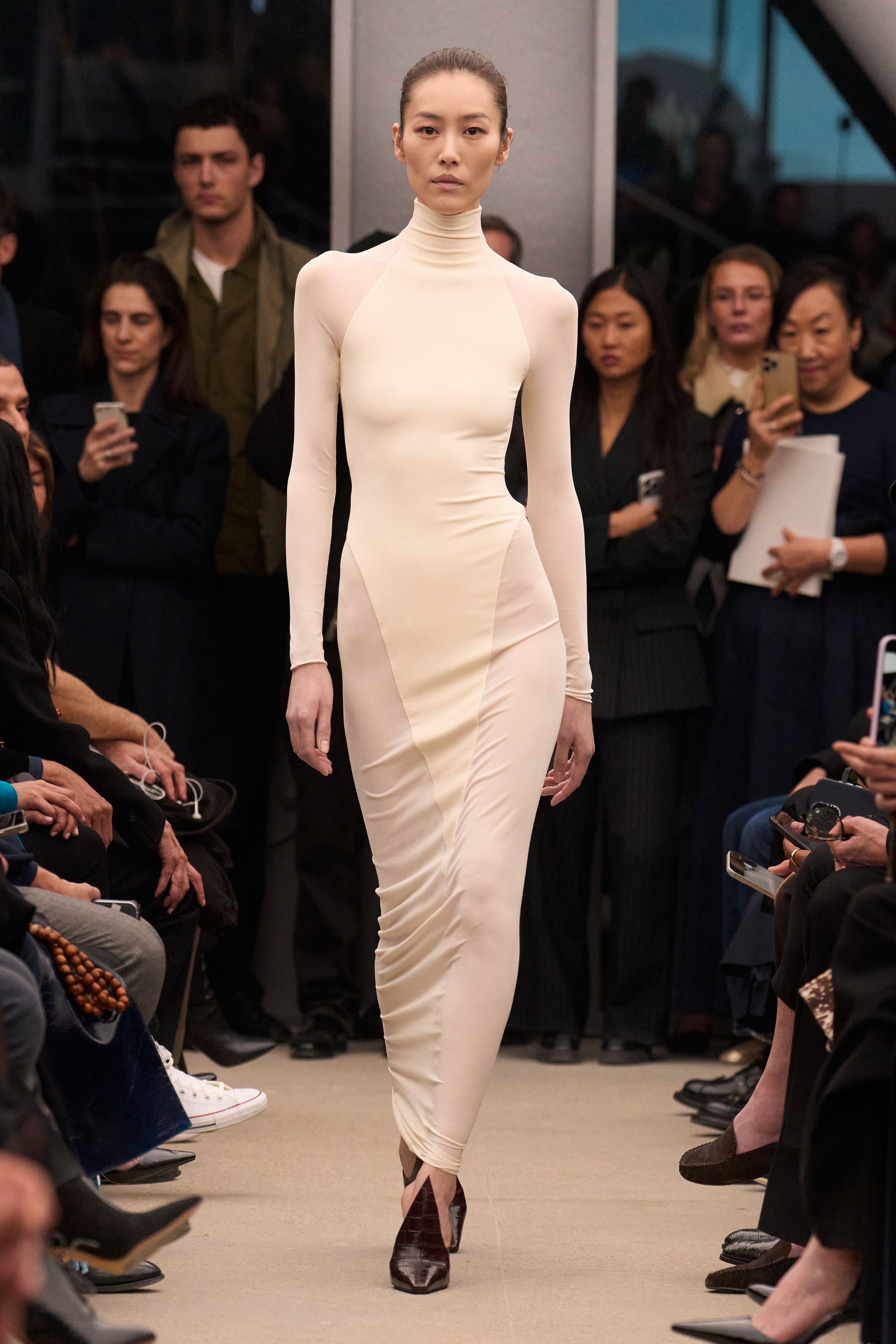 Alaïa继续以雕塑般的女性身体线条为核心，呈现极致精准的剪裁与材质张力。贴身针织长裙、立体外套与收腰大衣展现品牌标志性的曲线美学，整体色调以米色、酒红与深棕为主，营造出沉稳而性感的高级氛围。轮廓简洁却充满力量，既强调女性身体曲线，又通过结构性裁剪赋予服装雕塑般的建筑感，让极简主义与性感力量达到平衡-顽石频道趋势研究